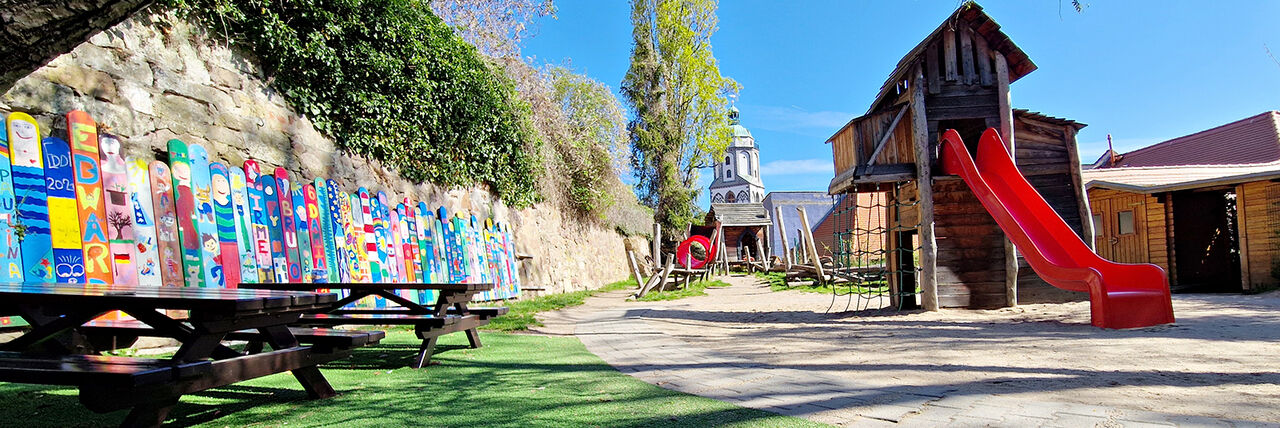 Spielplatz mit Rutsche, Kirchturm im Hintergrund