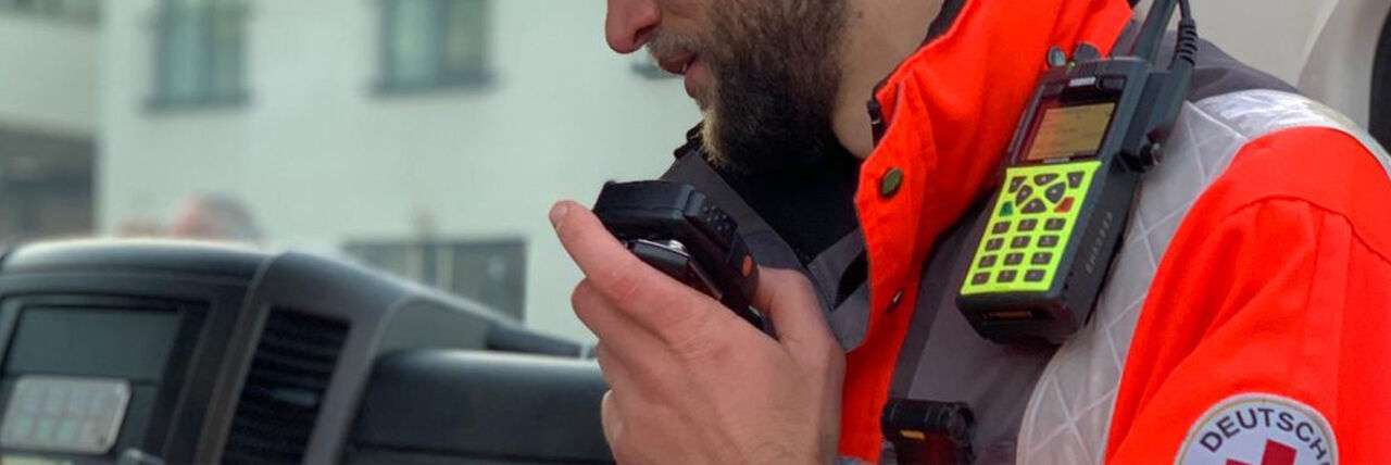 DRK-Einsatzkraft spricht in Handsprechfunkgerät