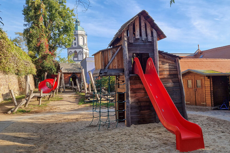 Spielplatz mit Rutsche, Spielhaus, Altstadtturm im Hintergrund