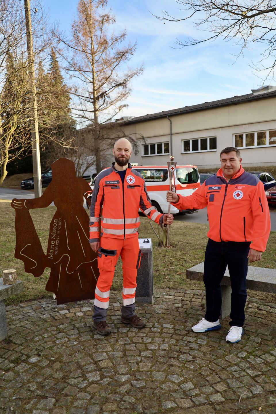 Zwei Personen in DRK-Uniform halten eine Fackel