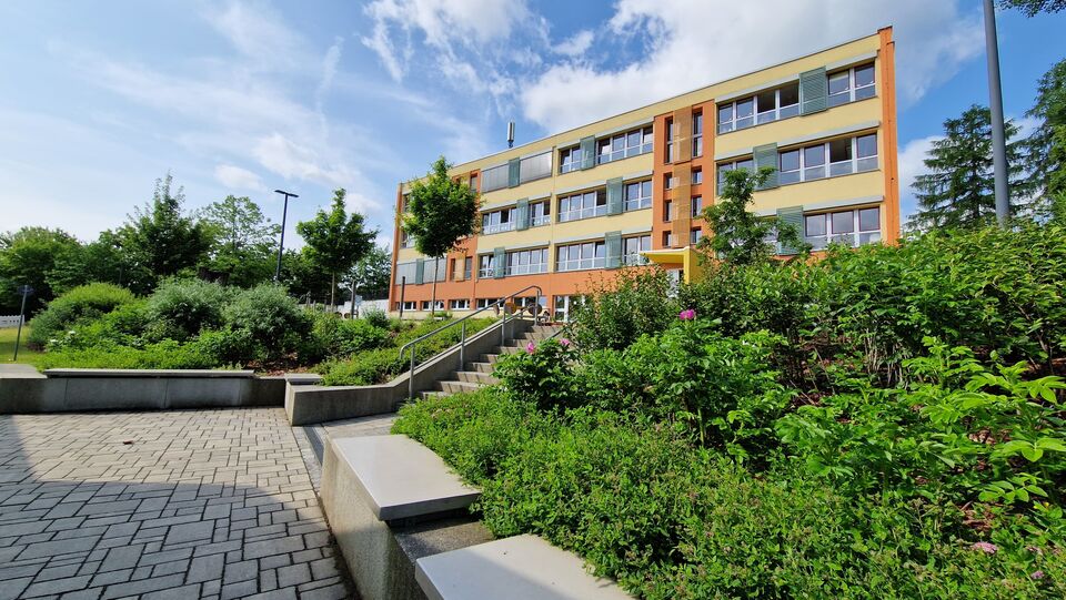 Schulgebäude mit grünen Büschen